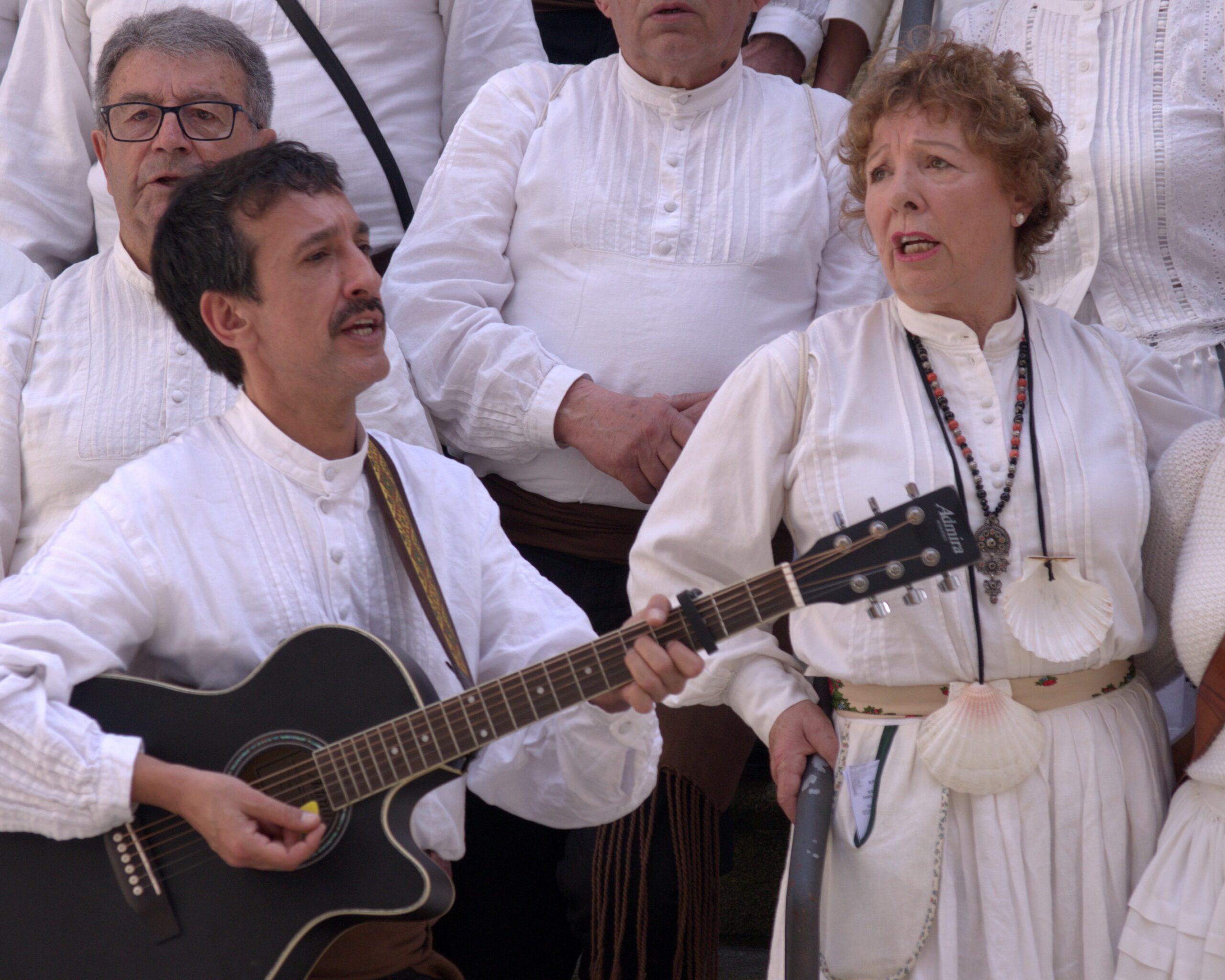 Músicos de Máis Cantos cantando e tocando a guitarra durante unha actuación tradicional galega.